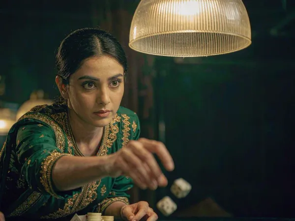 m66 Woman reaches towards white dice on green felt among chips and playing cards